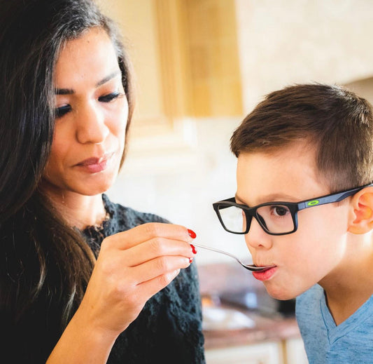 Mom feeding her child elderberry syrup for immune support