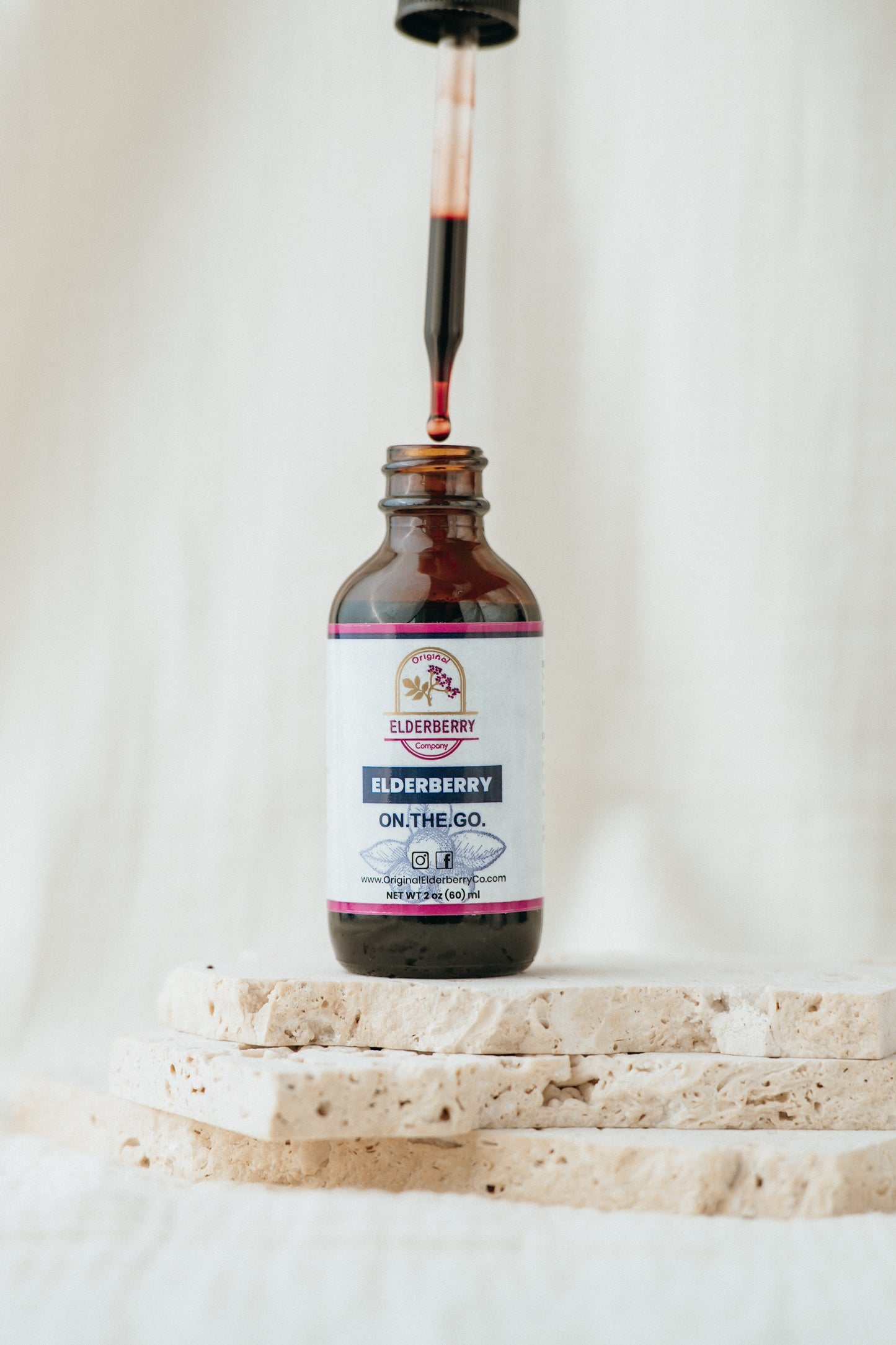 Bottle of Elderberry On The Go syrup being poured into a glass on a white background