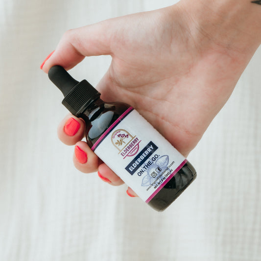 Hand holding a bottle with a dropper against a neutral background